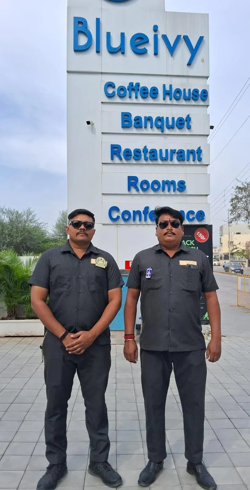 Two guards beside a hotel and banquet venue signboard
