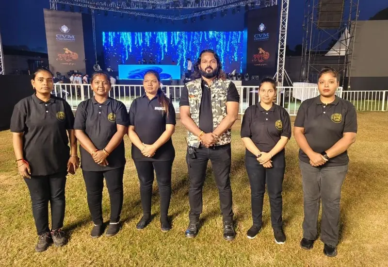 Six women and men of the GHS team standing on grass in front of an event stage